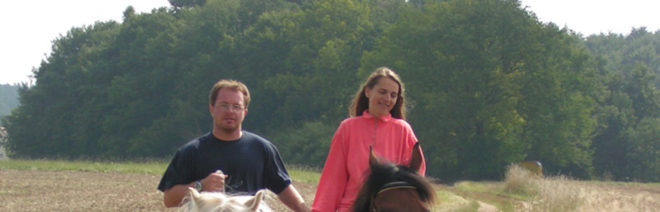 Ein Mann und eine Frau auf ihren Pferden auf einem Feldweg.